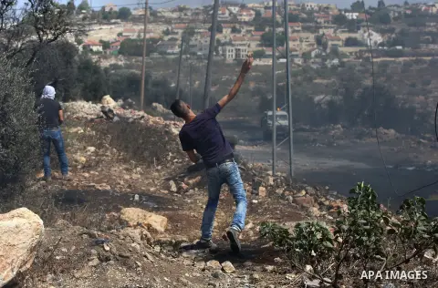 A Palestinian protester throws a stone towards Israeli security forces during clashes following a demonstration against the expropriation of Palestinian land by Israel in the village of Kfar Qaddum, near Nablus in the oc...