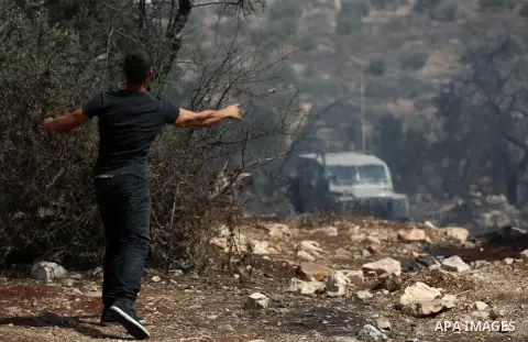 A Palestinian protester throws a stone towards Israeli security forces during clashes following a demonstration against the expropriation of Palestinian land by Israel in the village of Kfar Qaddum, near Nablus in the oc...