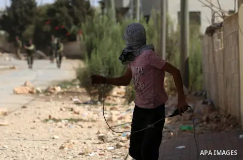 A Palestinian protester throws a stone towards Israeli security forces during clashes following a demonstration against the expropriation of Palestinian land by Israel in the village of Kfar Qaddum, near Nablus in the oc...