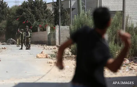 A Palestinian protester throws a stone towards Israeli security forces during clashes following a demonstration against the expropriation of Palestinian land by Israel in the village of Kfar Qaddum, near Nablus in the oc...
