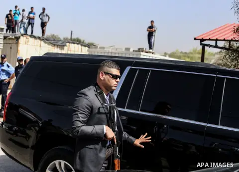 Palestinian security officers surround the vehicle carrying Prime Minister Rami Hamdallah upon his arrival with his government at Erez crossing in the northern Gaza Strip on October 2, 2017. Palestinian prime minister Ra...