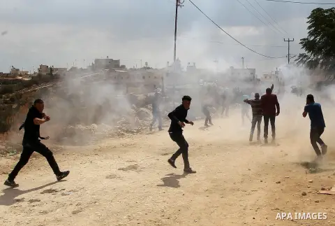 Palestinian protesters run for cover during clashes with Israeli security forces at a protest demanding the reopening of the main road to the Qalqas village that was closed by Israel almost 17 years ago in the West Bank...