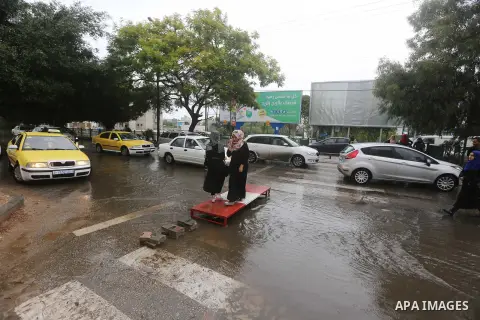 Palestinian students walk in a street flooded by rain water, in Gaza city on October 9, 2017. Photo by Atia Darwish