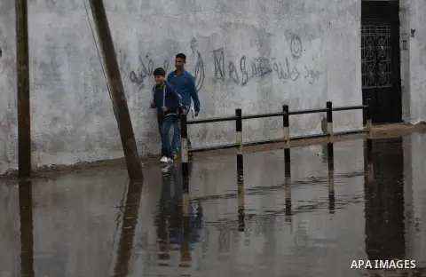 Palestinian students walk in a street flooded by rain water, in Gaza city on October 9, 2017. Photo by Mohammed Asad