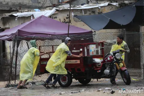 Palestinian boys help people during heavy rain, in Gaza city on October 9, 2017. Photo by Mohammed Asad