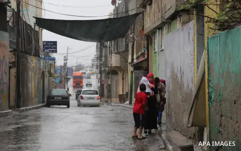 Palestinians walk in a street flooded by rain water, in Gaza city on October 9, 2017. Photo by Mohammed Asad