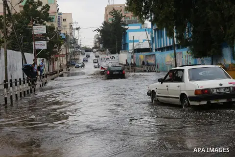 Palestinian students walk in a street flooded by rain water, in Gaza city on October 9, 2017. Photo by Mohammed Asad