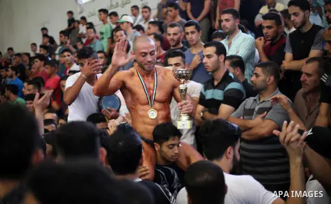 A Palestinian participant carries a cup after he wins in a bodybuilding competition, which organized by Palestinian Federation of Bodybuilding and Fitness (PFBB), in Gaza city on October 20, 2017. Photo by Mohammed Asad