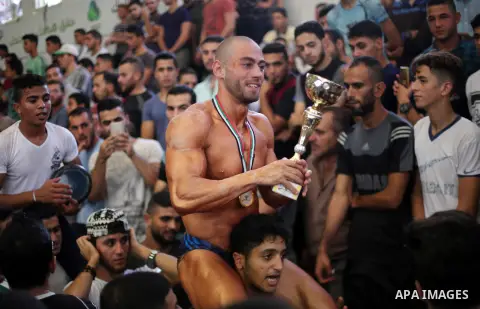 A Palestinian participant carries a cup after he wins in a bodybuilding competition, which organized by Palestinian Federation of Bodybuilding and Fitness (PFBB), in Gaza city on October 20, 2017. Photo by Mohammed Asad