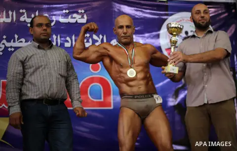 A Palestinian participant carries a cup after he wins in a bodybuilding competition, which organized by Palestinian Federation of Bodybuilding and Fitness (PFBB), in Gaza city on October 20, 2017. Photo by Mohammed Asad