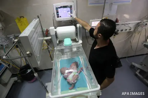 A Palestinian nurse tends to one-day-old Palestinian conjoined twins boys (Siamese twin) from the Ghanem family with one body but two heads, in an incubator at the neonatal intensive care unit at Shifa hospital in Gaza c...