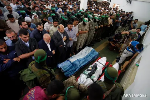 Palestinian mourners and fighters from the Ezzedine al-Qassam Brigades, the armed wing of the Palestinian Hamas movement pray around the bodies of 30-year-old Mosbah Shabir and Mohammed Alagha,22, in Khan Yunis, in the s...