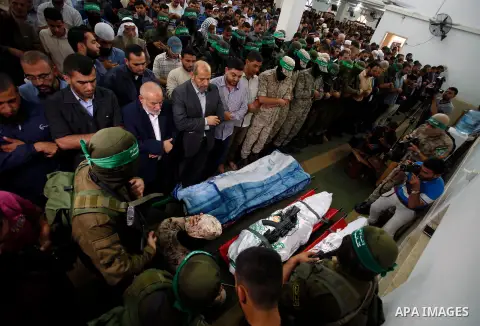 Palestinian mourners and fighters from the Ezzedine al-Qassam Brigades, the armed wing of the Palestinian Hamas movement pray around the bodies of 30-year-old Mosbah Shabir and Mohammed Alagha,22, in Khan Yunis, in the s...