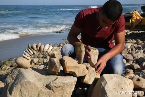 A Palestinian youth Ahmed Al Awadi performs rock balancing at the beach of Gaza city on November 16, 2017. Rock balancing is a performance art which involves arranging natural stones usually found on location, in gravity...