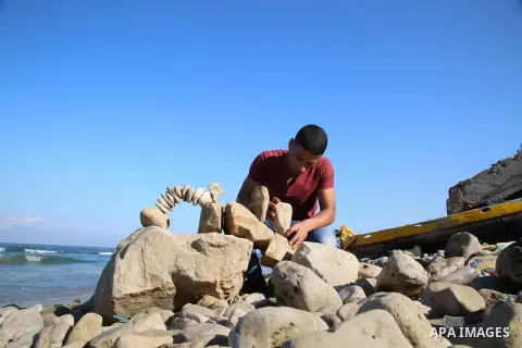A Palestinian youth Ahmed Al Awadi performs rock balancing at the beach of Gaza city on November 16, 2017. Rock balancing is a performance art which involves arranging natural stones usually found on location, in gravity...