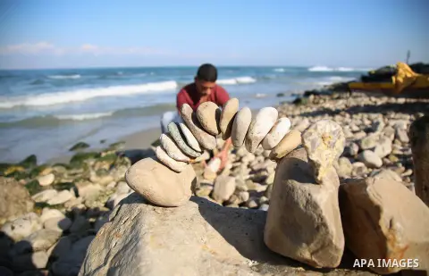 A Palestinian youth Ahmed Al Awadi performs rock balancing at the beach of Gaza city on November 16, 2017. Rock balancing is a performance art which involves arranging natural stones usually found on location, in gravity...