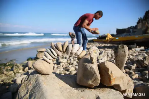 A Palestinian youth Ahmed Al Awadi performs rock balancing at the beach of Gaza city on November 16, 2017. Rock balancing is a performance art which involves arranging natural stones usually found on location, in gravity...