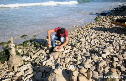 A Palestinian youth Ahmed Al Awadi performs rock balancing at the beach of Gaza city on November 16, 2017. Rock balancing is a performance art which involves arranging natural stones usually found on location, in gravity...