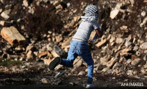 A Palestinian protester uses a slingshot to hurl stones towards Israeli security forces during clashes following a weekly demonstration against the expropriation of Palestinian land by Israel in the village of Kfar Qaddu...