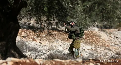 A member of Israeli security forces aims his weapon towards Palestinian protesters during clashes following a weekly demonstration against the expropriation of Palestinian land by Israel in the village of Kfar Qaddum, ne...