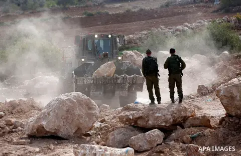 Israeli security forces stand guard as an Israeli army bulldozer closes a road in the West Bank city of Hebron after Palestinian municipality of Hebron reopened the road after 17 years of closure by the Israeli army in t...