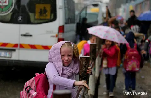 Palestinian school children walk in a flooded street during heavy rain in Gaza City on November 21, 2017. Photo by Ashraf Amra
