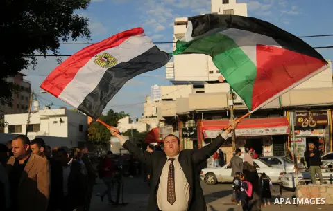 A Palestinian man waves the Palestinian and the Egyptian flag in in a mourning tent set up for people to pay their respects to the Egyptian victims after the deadly attack on a mosque in Egypt's Sinai, on November 26, 20...