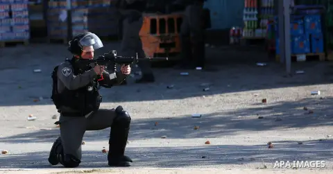 An Israeli soldier aims his weapon towards Palestinian protesters during clashes in the northern village of Qusra in the occupied West Bank near Nablus on December 1, 2017. Yesterday a Palestinian farmer Mahmoud Odeh, 48...