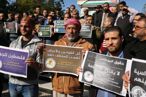 Palestinian employees of Gaza strip hold banners during a protest demanding their rights, in Gaza city, on December 4, 2017. Photo by Ashraf Amra