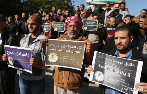 Palestinian employees of Gaza strip hold banners during a protest demanding their rights, in Gaza city, on December 4, 2017. Photo by Ashraf Amra