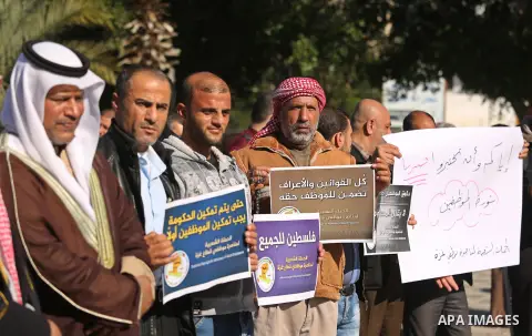 Palestinian employees of Gaza strip hold banners during a protest demanding their rights, in Gaza city, on December 4, 2017. Photo by Ashraf Amra