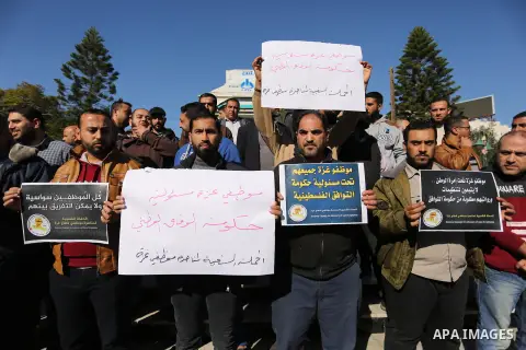 Palestinian employees of Gaza strip hold banners during a protest demanding their rights, in Gaza city, on December 4, 2017. Photo by Ashraf Amra