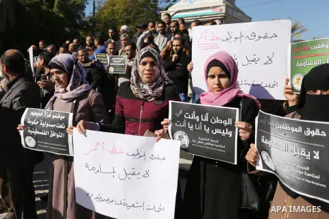 Palestinian employees of Gaza strip hold banners during a protest demanding their rights, in Gaza city, on December 4, 2017. Photo by Ashraf Amra