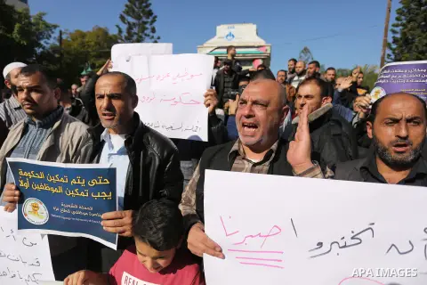 Palestinian employees of Gaza strip hold banners during a protest demanding their rights, in Gaza city, on December 4, 2017. Photo by Ashraf Amra