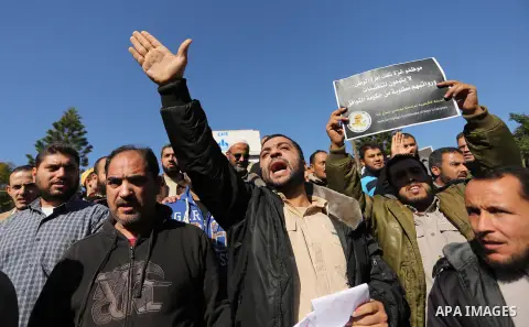 Palestinian employees of Gaza strip hold banners during a protest demanding their rights, in Gaza city, on December 4, 2017. Photo by Ashraf Amra