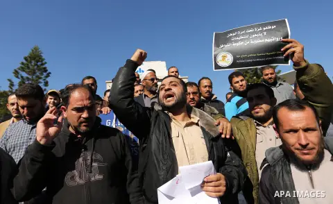 Palestinian employees of Gaza strip hold banners during a protest demanding their rights, in Gaza city, on December 4, 2017. Photo by Ashraf Amra