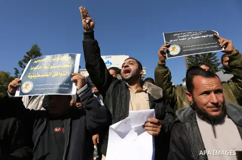 Palestinian employees of Gaza strip hold banners during a protest demanding their rights, in Gaza city, on December 4, 2017. Photo by Ashraf Amra