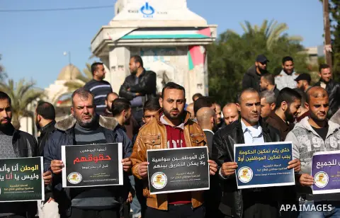 Palestinian employees of Gaza strip hold banners during a protest demanding their rights, in Gaza city, on December 4, 2017. Photo by Ashraf Amra
