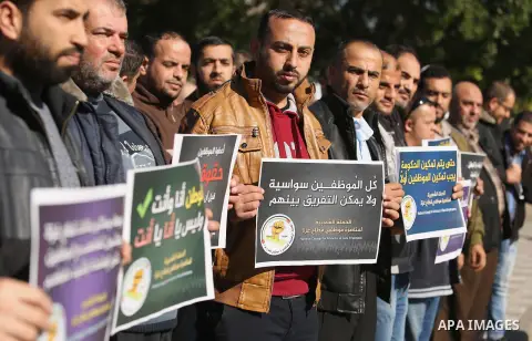 Palestinian employees of Gaza strip hold banners during a protest demanding their rights, in Gaza city, on December 4, 2017. Photo by Ashraf Amra