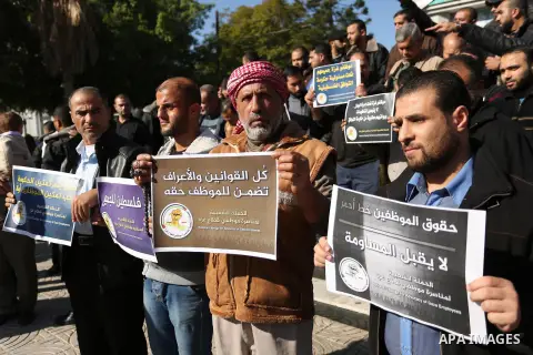Palestinian employees of Gaza strip hold banners during a protest demanding their rights, in Gaza city, on December 4, 2017. Photo by Ashraf Amra