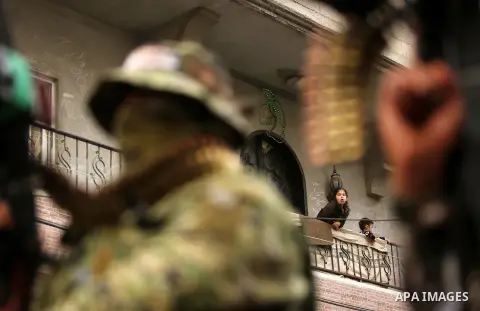Palestinians watch as members of the Ezzedine al-Qassam Brigades, the military wing of the Palestinian Islamist movement Hamas take part during a military parade ahead of the 30th anniversary of Hamas' founding, in Khan...