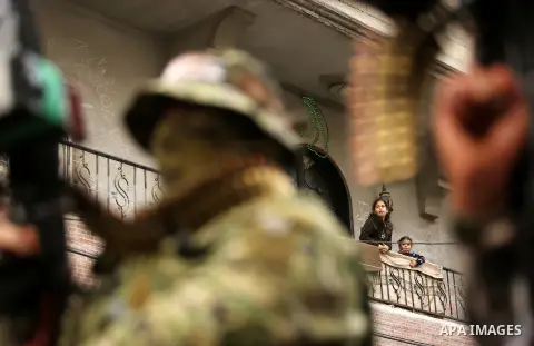 Palestinians watch as members of the Ezzedine al-Qassam Brigades, the military wing of the Palestinian Islamist movement Hamas take part during a military parade ahead of the 30th anniversary of Hamas' founding, in Khan...