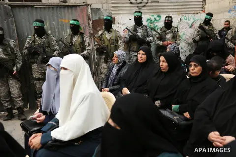 Palestinians watch as members of the Ezzedine al-Qassam Brigades, the military wing of the Palestinian Islamist movement Hamas take part during a military parade ahead of the 30th anniversary of Hamas' founding, in Khan...