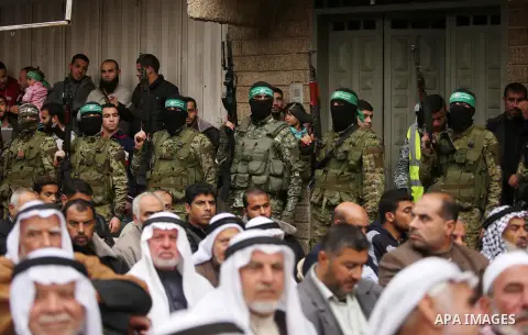 Palestinians watch as members of the Ezzedine al-Qassam Brigades, the military wing of the Palestinian Islamist movement Hamas take part during a military parade ahead of the 30th anniversary of Hamas' founding, in Khan...