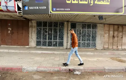A Palestinian man walks past closed shops during a general strike over U.S. President Donald Trump's decision to recognize Jerusalem as the capital of Israel, in the Gaza city on December 7, 2017. Photo by Ashraf Amra