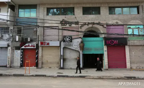 Palestinians walk past closed shops during a general strike over U.S. President Donald Trump's decision to recognize Jerusalem as the capital of Israel, in the Gaza city on December 7, 2017. Photo by Ashraf Amra