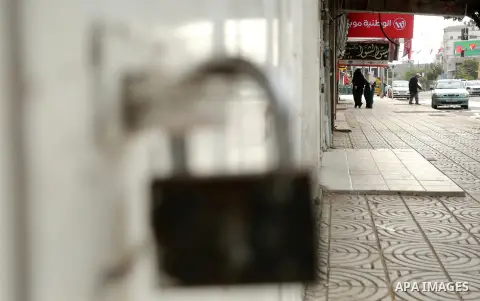 Palestinians walk past closed shops during a general strike over U.S. President Donald Trump's decision to recognize Jerusalem as the capital of Israel, in the Gaza city on December 7, 2017. Photo by Ashraf Amra