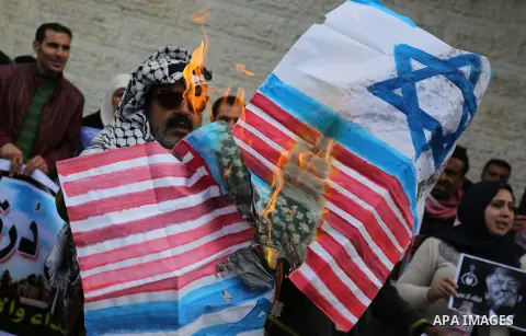Palestinians burn an Israeli flag and a U.S. flag during a protest against Trump's decision to recognize Jerusalem as the capital of Israel, in Gaza City December 11, 2017. Photo by Ashraf Amra