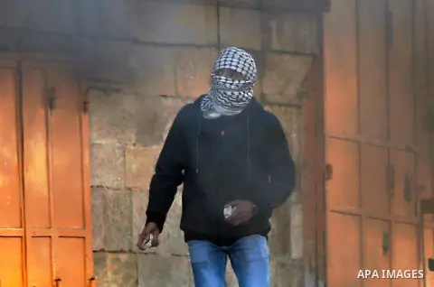 A Palestinian protester hurl stosnes towards Israeli secrity forces during clashes behind a checkpoint in the city centre of the West Bank town of Hebron on December 11, 2017 as demonstrations continue to flare in the Mi...