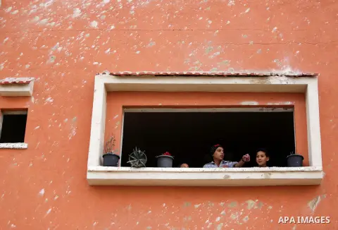 Palestinians look out from a damaged window of their house following an Israeli airstrike on a nearby Hamas base, in Khan Yunis town in the southern Gaza Strip in December 13, 2017. Photo by Ashraf Amra